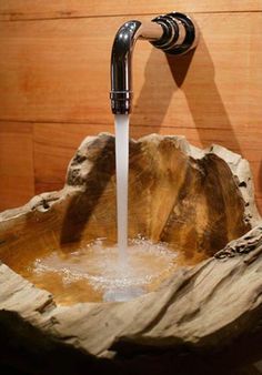 a wooden bowl sink with water running from the faucet