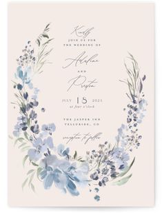 a wedding card with blue flowers and greenery in the middle, on a white background