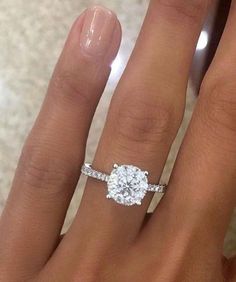 a woman's hand with a engagement ring on it and a diamond in the middle