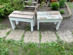 two small wooden tables sitting on top of a brick walkway in front of a house