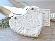 a white heart shaped ornament sitting on top of a table next to a pair of scissors