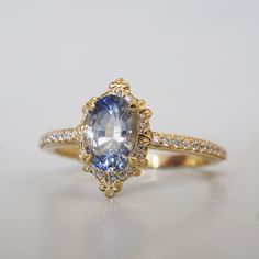 an oval shaped blue and white sapphire ring with diamond accents in yellow gold plated setting