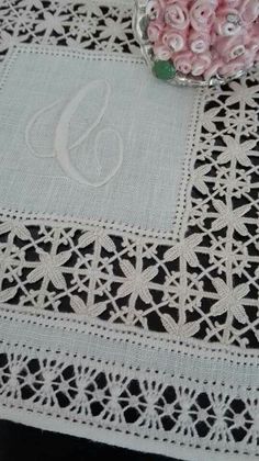 a white doily with pink flowers and a monogrammed tablecloth on it