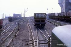 an old train traveling down tracks next to a tall building and another one on the other side