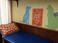 a blue bench sitting in front of a wall with pictures on it and two pillows