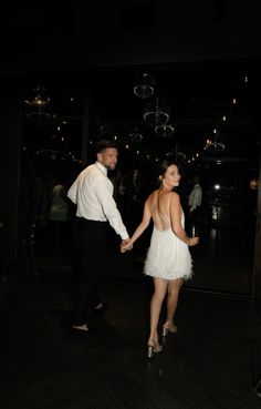 a man and woman holding hands while standing next to each other on a dance floor