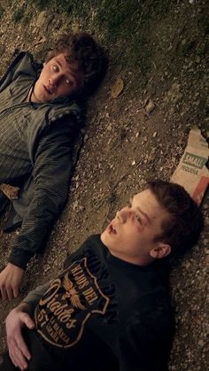 two young men laying on the ground next to each other, looking up at something