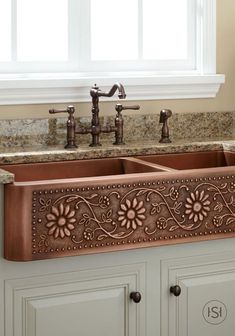 a kitchen sink with an ornate design on the front and side panel, in copper