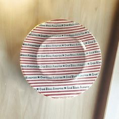 a red and white striped plate sitting on top of a wooden table next to a wall