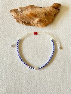 - Discover the unique charm of our adjustable bracelet, expertly handcrafted with navy Miyuki beads, striped Czech beads, and a single freshwater pearl that adds a touch of elegance. A vibrant red Miyuki bead provides a stunning contrast, making this piece perfect for accessorizing any outfit. 🌟 📏 Adjustable design to fit any wrist size comfortably. 🌊 Navy and white striped Czech beads create a classic nautical look. ❤️ Single red Miyuki bead adds a pop of color. 🔳 Features a solitary freshw Adjustable Jubilee Beaded Bracelets For Friendship, Adjustable Beaded Bracelets With Letter Beads As Souvenir, Adjustable Braided Bracelet With Letter Beads, Adjustable Blue Braided Bracelet With Colorful Beads, Handmade White Beaded Bracelets As Souvenir, Adjustable Blue Hand-strung Braided Bracelets, Adjustable White Bracelet Souvenir, Casual Blue Beaded Bracelets, Navy Adjustable Casual Bracelets