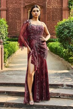 Maroon gown with sequin, cutdana, bead embroidery and draped on one sleeve. - Aza Fashions Glamorous Draped Festive Dresses, Glamorous Draped Dresses For Festive Occasions, Festive Draped Glamorous Dresses, Festive Party Gown With Sweep Train, Festive Floor-length Evening Sequin Fabric, Festive Floor-length Sequin Fabric For Evening, Floor-length Wedding Gown With Side Slits, Elegant Draped Hand Embellished Dresses, Festive Gala Evening Dress With Cape Sleeves