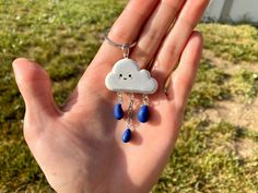 a hand is holding a tiny cloud and raindrops on it's chain