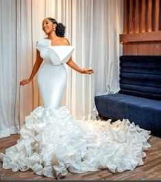 a woman in a white dress standing next to a couch