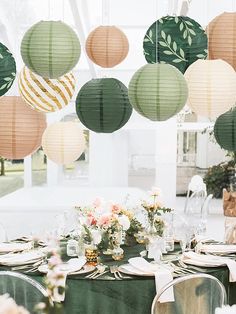 the table is set with green linens and paper lanterns