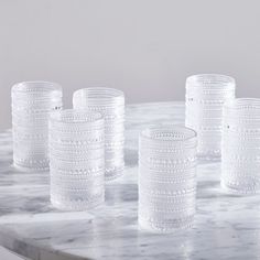 five clear glass cups sitting on top of a marble table