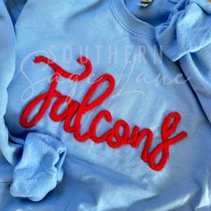 Pullover embroidered with cursive chenille The word Falcons with your team colors. Chenille Color Options: White, Black, Crimson, Maroon, Royal, Navy, Sage, Olive, Pine, Gray, Pale Blue, Aqua Blue, Teal, Mushroom, Bright Yellow, Yellow Gold, Cream, Coral Orange, Neon Orange, Purple. Please message us for custom colors or with any questions. *We use only the highest quality Gildan Heavy Blend Unisex Sweatshirts Crew Neck T-shirt With Letter Embroidery For College, Varsity T-shirt With Embroidered Graphics For Fall, Collegiate Long Sleeve T-shirt With Letter Embroidery, Collegiate College Tops With Embroidered Logo, Collegiate Tops With Embroidered Logo For College, Collegiate Tops With Embroidered Graphics For College, Crew Neck Top With Embroidered Logo For College, Team-colored Cotton Tops With Embroidered Graphics, Team-colored Tops With Embroidered Logo For College