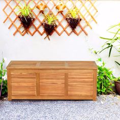 a wooden bench sitting in front of a wall mounted planter and potted plants