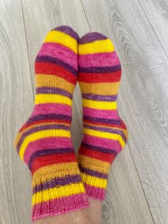 Bright Striped Hand-Knitted Socks, wool knitted socks for cold days and cozy evening.  These unique socks are hand-knitted from high-quality hand-dyed socks yarn. The bright stripes in of pink, yellow, red and purple will add vibrancy and joy any outfit.  These socks are knitted with perfect pattern that neither stretches nor slips on the foot. The thickness of the product is such that the knitted socks can be worn in shoes.    A high percentage of wool in the product makes the knitted socks very warm and cozy, while the polyamide thread gives the socks strength and durability, extending their lifespan from many years. Perfect gift: These socks make an excellent gift for lovers of bright and original items. Perfect for cold days and cozy evenings. Suitable for size 37-39 (EU)  Care Instruc Dyed Socks, Patchwork Knit, Hand Dyed Sock Yarn, Unique Socks, Cozy Evening, Bright Stripes, Knitted Socks, Red And Purple, Wool Socks