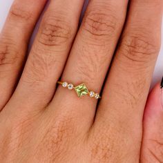 a woman's hand with a ring on it that has green and white stones