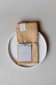 two napkins tied together on a plate with a tag attached to the top one