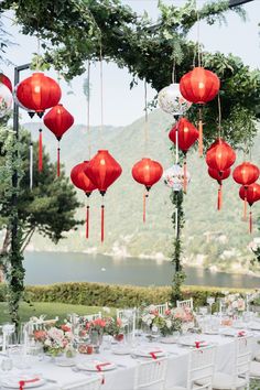 an outdoor wedding with red lanterns hanging from the ceiling and tables set up for dinner