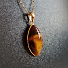 ITEM DESCRIPTION: >>The pendant is made from Solid 14K Yellow Gold. Gemstone used is absolutely natural and ethically sourced. >>Natural Tiger Eye in cabochon marquise shape with bezel setting is studded on it with utmost precision. >>This is a minimalist design and is absolutely hassle-free and everyday jewelry. Gem: Tiger Eye Gem size: 12x22 mm Marquise Gem weight: 11.55 carats Gold purity: 14K (58.33% approx.) Gold weight: 0.58 grams Gross weight: 2.89 grams The Gold purity is guaranteed and Teardrop Bezel Set Necklace Gift, Teardrop Pendant Jewelry With Bezel Setting, Gift Jewelry Teardrop Pendant With Bezel Setting, Gift Jewelry With Bezel Setting In Teardrop Pendant Shape, Gift Teardrop Pendant Jewelry With Bezel Setting, Elegant Marquise Gemstones For Gift, Gold Pendant Gemstones As A Gift, Gold Pendant Gemstones For Gift, Teardrop Cabochon Necklace For Anniversary