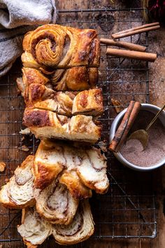 cinnamon rolls on a cooling rack with cinnamon sticks