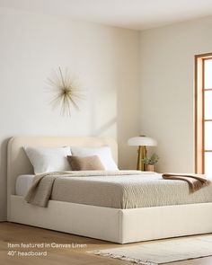 a white bed sitting next to a window on top of a hard wood floored floor