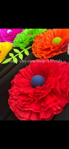 four different colored paper flowers on a table