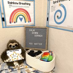 a stuffed animal sitting on top of a bed next to a sign that reads rainbow breathing calm down corner you matter