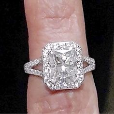 a woman's engagement ring with a cushion cut diamond surrounded by pave diamonds