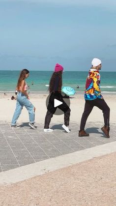 four people playing frisbee on the beach with one person running towards the camera