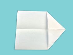 an origami paper folded in half on a blue background with one corner missing