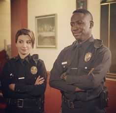 two police officers standing next to each other in an office building with their arms crossed