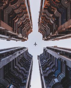 an airplane is flying through the air between two buildings