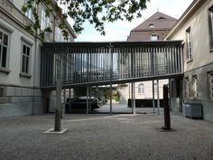 a car is parked under an overpass in the middle of a courtyard with tall buildings