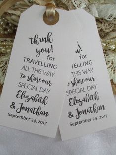 two white tags with black writing on them are hanging from a lace covered tablecloth