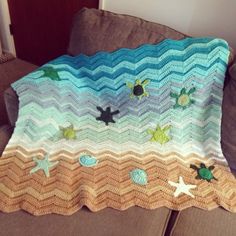 a crocheted blanket with sea turtles and starfishs on it sitting on a couch