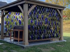 a wooden gazebo with glass bottles all over the top and side walls on it