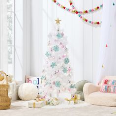 a white christmas tree with snowflakes and presents in front of it on the floor