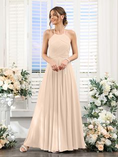 a woman standing in front of flowers wearing a long, halter - neck bridesmaid dress