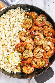 shrimp and rice in a skillet with lemon wedges on the side for garnish