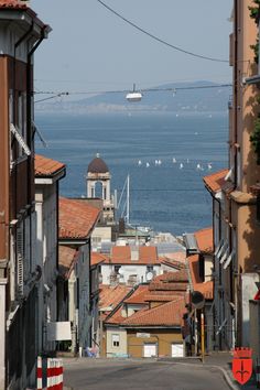 an empty street with buildings and boats in the water behind it on a sunny day