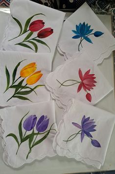 four napkins with flowers painted on them