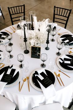 the table is set with black and white plates, napkins, silverware, and centerpieces