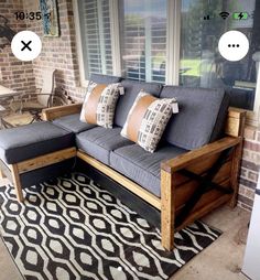 a couch sitting on top of a black and white rug next to a brick wall