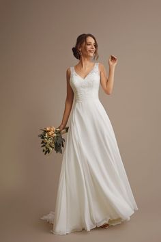 a woman in a white wedding dress holding a bouquet and posing for the camera with her hand up