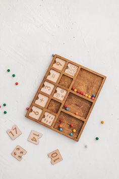 an assortment of wooden numbers and shapes on a white surface with colored beads scattered around