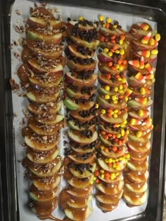 there are many donuts covered in candy and toppings on the tray, including apples