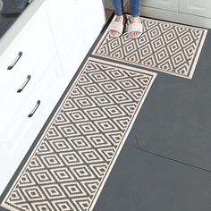 a woman standing on top of a kitchen floor next to a sink and stovetop